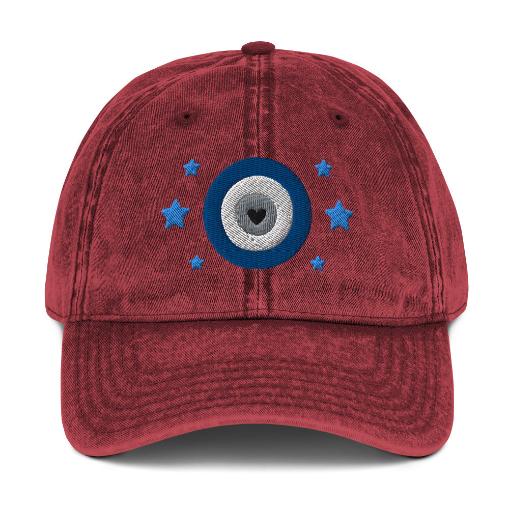 vintage denim cap maroon, with image design of blue eye of protection/evil eye/third eye, with stars. Front view.