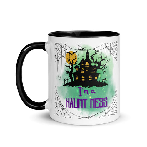 11 oz. white ceramic coffee/tea mug with solid black handle, rim, and inside. Image Design: a silhouette of a haunted house, with a moon behind it, and cosmic green cloud behind image. Spider webs in each corners of image. Image phrase: I'm a Haunt Mess. Left hand side view. Halloween, spooky season.