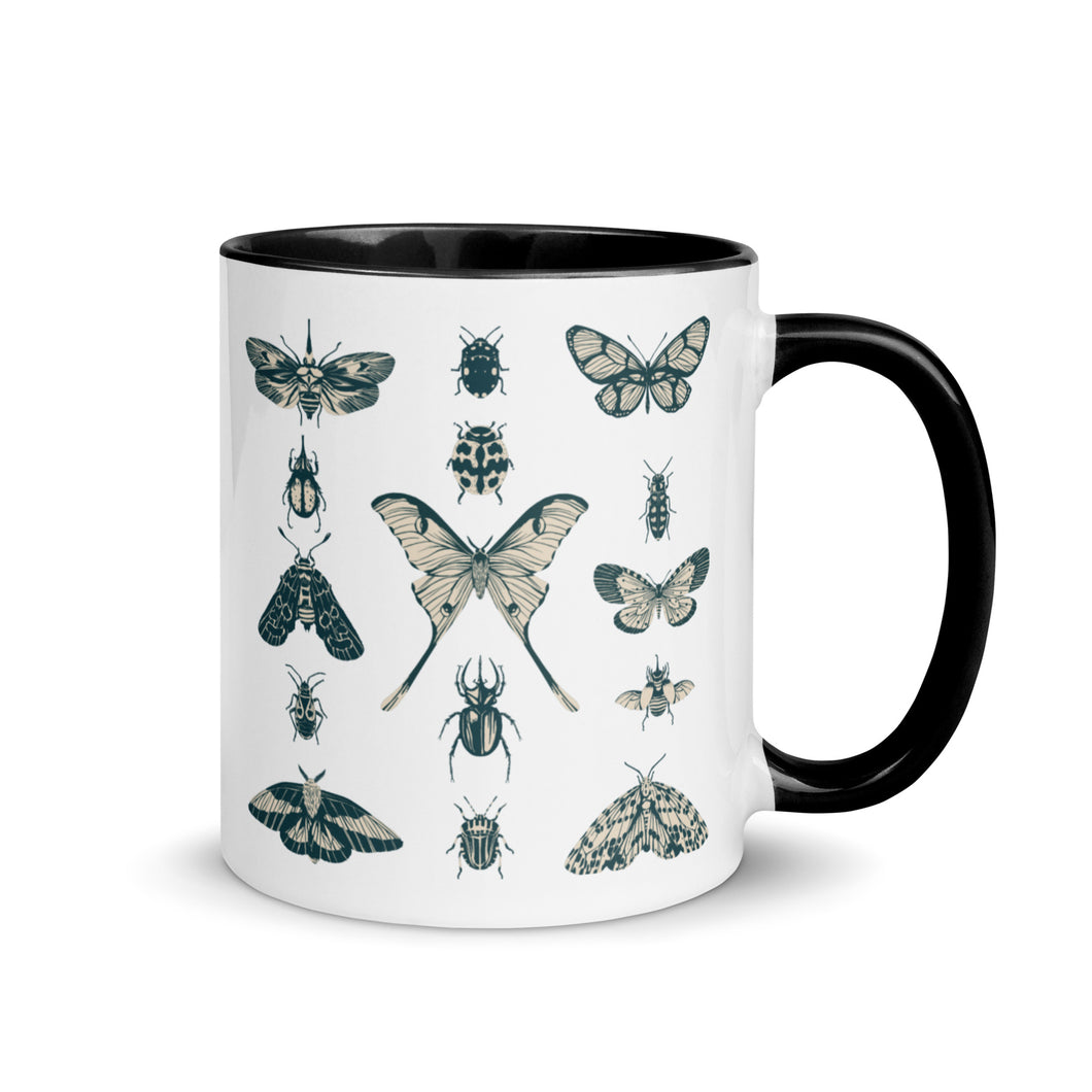 11 oz. white ceramic coffee/tea mug with solid black handle, rim, and inside. Image Design:  vintage beige and blue print images of various moths, butterflies, and beetles, all arranged in rows and columns. Right hand side view. Halloween, spooky season.