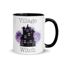 Load image into Gallery viewer, 11 oz. white ceramic coffee/tea mug with solid black handle, rim, and inside. Image Design: silhouette of black haunted house, cosmic purple cloud in background. Image phrase: Village witch. Right hand side view. Halloween, spooky season.
