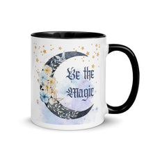 Load image into Gallery viewer, 11 oz. white ceramic coffee/tea mug with solid black handle, rim, and inside. Image Design: watercolor blue crescent moon, with flowers, daisies, lilies, butterflies. Stars in background, smoky purple background. Image phrase: Be the Magic. Right hand side view. Halloween, spooky season.
