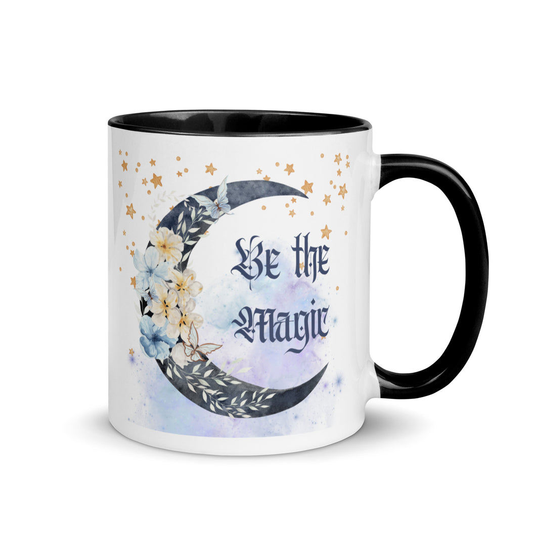 11 oz. white ceramic coffee/tea mug with solid black handle, rim, and inside. Image Design: watercolor blue crescent moon, with flowers, daisies, lilies, butterflies. Stars in background, smoky purple background. Image phrase: Be the Magic. Right hand side view. Halloween, spooky season.