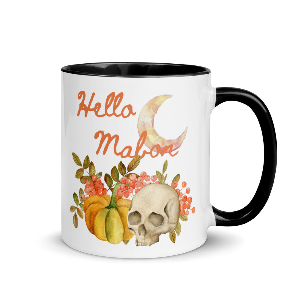 11 oz. white ceramic coffee/tea mug with solid black handle, rim, and inside. Image Design:  watercolor pumpkin, and skull, leaves and berries behind. Crescent moon in background. Image phrase: Hello Mabon. Right hand side view. Halloween, spooky season.