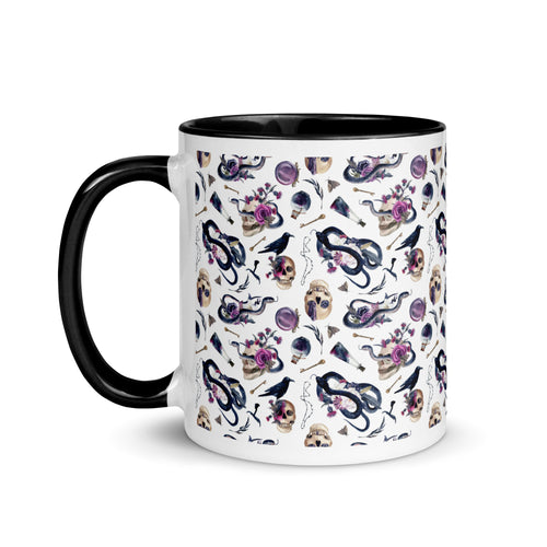 11 oz. white ceramic coffee/tea mug with solid black handle, rim, and inside. Image Design: gothic theme patter of skulls, wands, snakes, ravens, purple flowers. left hand side view. 
Halloween, spooky season.