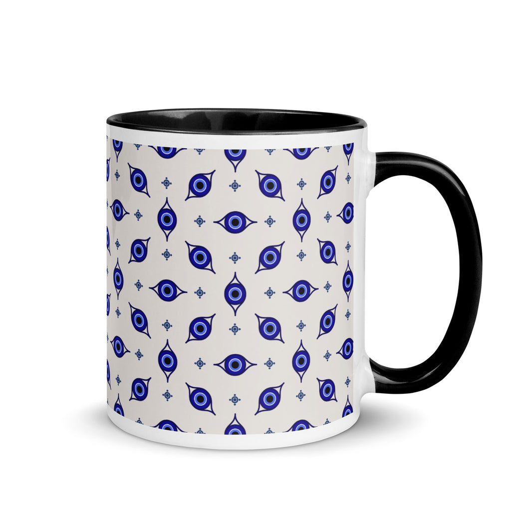 11 oz. white ceramic coffee/tea mug with solid black handle, rim, and inside. Wrapped around mug is patterned image of eye of protection/evil eye. Right hand side view.