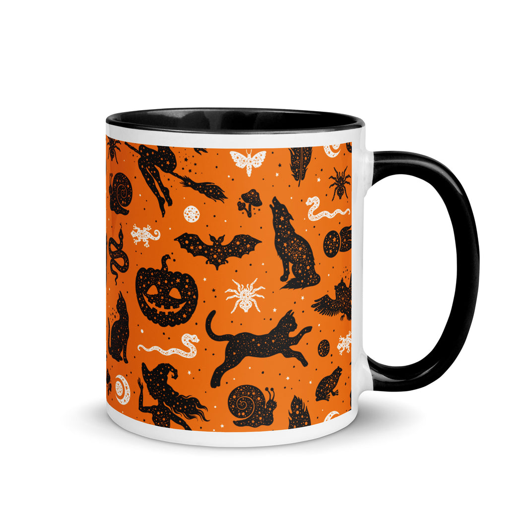 11 oz. white ceramic coffee/tea mug with solid black handle, rim, and inside. Image Design: Halloween theme pattern of witch's familiars, witch on broom, pumpkins, snakes, lizards, spiders, moon crescent, owls, cats, moths, background color is orange, with a cosmic tone. right hand side view. Halloween, spooky season.