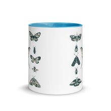 Load image into Gallery viewer, 11 oz. white ceramic coffee/tea mug with solid light blue handle, rim, and inside. Image Design:  vintage beige and blue print images of various moths, butterflies, and beetles, all arranged in rows and columns. Center front view. Halloween, spooky season.
