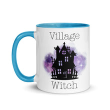 Load image into Gallery viewer, 11 oz. white ceramic coffee/tea mug with solid light blue handle, rim, and inside. Image Design: silhouette of black haunted house, cosmic purple cloud in background. Image phrase: Village witch. Left hand side view. Halloween, spooky season.
