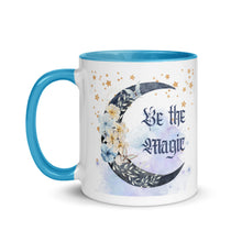 Load image into Gallery viewer, 11 oz. white ceramic coffee/tea mug with solid light blue handle, rim, and inside. Image Design: watercolor blue crescent moon, with flowers, daisies, lilies, butterflies. Stars in background, smoky purple background. Image phrase: Be the Magic. left hand side view. Halloween, spooky season.
