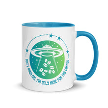 Load image into Gallery viewer, 11 oz. white ceramic coffee/tea mug with solid light blue handle, rim, and inside. Image Design: ufo ship abducting/beaming up coffee beans. background blue to light green gradient, stars. Text under image: &quot;Don&#39;t mind me, I&#39;m only here for the Coffee.&quot; Right hand side view.
