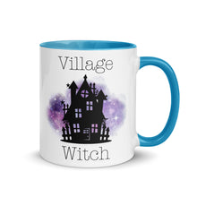 Load image into Gallery viewer, 11 oz. white ceramic coffee/tea mug with solid light blue handle, rim, and inside. Image Design: silhouette of black haunted house, cosmic purple cloud in background. Image phrase: Village witch. Right hand side view. Halloween, spooky season.
