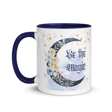 Load image into Gallery viewer, 11 oz. white ceramic coffee/tea mug with solid navy blue handle, rim, and inside. Image Design: watercolor blue crescent moon, with flowers, daisies, lilies, butterflies. Stars in background, smoky purple background. Image phrase: Be the Magic. left hand side view. Halloween, spooky season.
