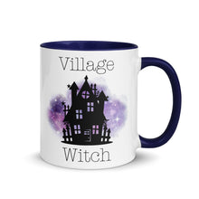 Load image into Gallery viewer, 11 oz. white ceramic coffee/tea mug with solid navy blue handle, rim, and inside. Image Design: silhouette of black haunted house, cosmic purple cloud in background. Image phrase: Village witch. Right hand side view. Halloween, spooky season.
