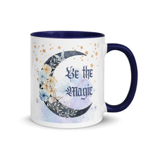 Load image into Gallery viewer, 11 oz. white ceramic coffee/tea mug with solid navy blue handle, rim, and inside. Image Design: watercolor blue crescent moon, with flowers, daisies, lilies, butterflies. Stars in background, smoky purple background. Image phrase: Be the Magic. Right hand side view. Halloween, spooky season.
