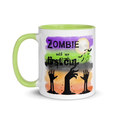 11 oz. white ceramic coffee/tea mug with solid light green handle, rim, and inside. Image Design: silhouette of zombie hands reaching out of ground, background colors orange, light orange, grey-black, light green, purple, moon and bats in background. Image phrase: Zombie until my first cup. left hand side view. Halloween, spooky season.