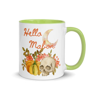 11 oz. white ceramic coffee/tea mug with solid light green handle, rim, and inside. Image Design:  watercolor pumpkin, and skull, leaves and berries behind. Crescent moon in background. Image phrase: Hello Mabon. Right hand side view. Halloween, spooky season.