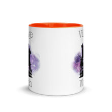 Load image into Gallery viewer, 11 oz. white ceramic coffee/tea mug with solid dark orange handle, rim, and inside. Image Design: silhouette of black haunted house, cosmic purple cloud in background. Image phrase: Village witch. Center front view. Halloween, spooky season.
