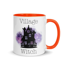 Load image into Gallery viewer, 11 oz. white ceramic coffee/tea mug with solid dark orange handle, rim, and inside. Image Design: silhouette of black haunted house, cosmic purple cloud in background. Image phrase: Village witch. Right hand side view. Halloween, spooky season.
