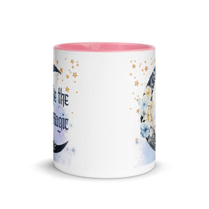 11 oz. white ceramic coffee/tea mug with solid light pink handle, rim, and inside. Image Design: watercolor blue crescent moon, with flowers, daisies, lilies, butterflies. Stars in background, smoky purple background. Image phrase: Be the Magic. Center front view. Halloween, spooky season.