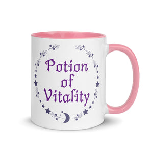 11 oz. white ceramic coffee/tea mug with solid light pink handle, rim, and inside. Image Design: Purple words 'Potion of Vitality' bordered by stars, leaves, and crescent moon at the bottom. Image phrase: Potion of Vitality. Right hand side view. Halloween, spooky season.