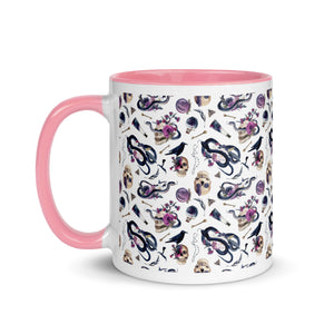 11 oz. white ceramic coffee/tea mug with solid pink handle, rim, and inside. Image Design: gothic theme patter of skulls, wands, snakes, ravens, purple flowers. left hand side view. 
Halloween, spooky season.