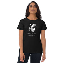 Load image into Gallery viewer, Woman modeling/wearing woman&#39;s black t-shirt with image phrase: Make Peace, Not War, underneath an image of a skeleton hand in the gesture of a peace sign, holding a daisy flower. Front view. Halloween, spooky season.
