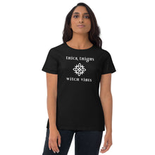 Load image into Gallery viewer, Woman modeling/wearing woman&#39;s black t-shirt with image phrase: thick thighs, witch vibes. Witch&#39;s knot, with crescent moons, and star in the middle. Front view. Halloween, spooky season.
