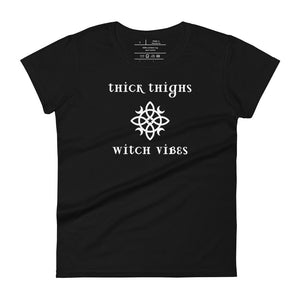 Woman's black t-shirt with image phrase: thick thighs, witch vibes. Witch's knot, with crescent moons, and star in the middle. Front view. Halloween, spooky season.