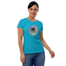 Load image into Gallery viewer, woman modeling/wearing women&#39;s caribbean blue t-shirt, with image design: side profile of a skull wearing a crown/hat of black roses, red berries, thorny vines and leaves, with a blue-purple moon behind it. Front View.
