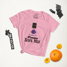 Load image into Gallery viewer, Woman&#39;s light pink t-shirt with image phrase: Practice safe Hex (play on words for &#39;Practice safe sex.&#39; Above phrase is a spell book, a cauldron, a wand. Front view. Halloween, spooky season.
