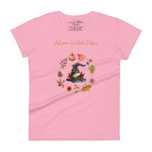 Load image into Gallery viewer, Woman&#39;s light pink t-shirt with image phrase in light orange font: Autumn Witch Vibes, with image of picturebook witch hat adorned with brown vines, autumn leaves, red-orange berries. A circle of leaves, acorns, pinecone, daisy flower, and mushroom, encircled the hat. Front view. Halloween, spooky season.
