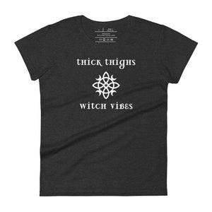 Woman's dark heather grey t-shirt with image phrase: thick thighs, witch vibes. Witch's knot, with crescent moons, and star in the middle. Front view. Halloween, spooky season.