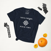 Load image into Gallery viewer, Woman&#39;s navy blue t-shirt with image phrase: thick thighs, witch vibes. Witch&#39;s knot, with crescent moons, and star in the middle. Front view. Halloween, spooky season.
