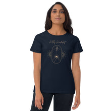 Load image into Gallery viewer, Woman modeling/wearing woman&#39;s navy blue t-shirt with image phrase: Witchy Wanderlust. Image under phrase is a minimalist hill with a sun behind, stars in the sky, and crystal suspended above the hill. Bordered with crescent moon on either side. Front view. Halloween, spooky season.
