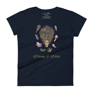 Woman's navy blue t-shirt with image phrase: Witchy & Wild, with image of woman's head with antlers, and stars in her hair. Circling her head are crystals, frog, snail, fern leaf, bunch of flowers, mushroom. Front view. Halloween, spooky season.