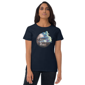 woman modeling/wearing women's navy blue t-shirt with image design of a dark moon, with a colorful dawn cloud in front, with image phrase: "Darkness precedes the Dawn." Front View.