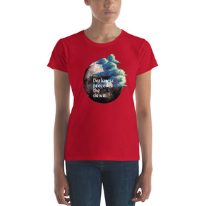 woman modeling/wearing women's true red t-shirt with image design of a dark moon, with a colorful dawn cloud in front, with image phrase: "Darkness precedes the Dawn." Front View.