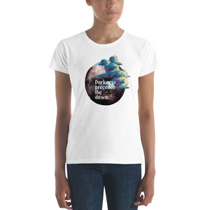 woman modeling/wearing women's white t-shirt with image design of a dark moon, with a colorful dawn cloud in front, with image phrase: "Darkness precedes the Dawn." Front View.